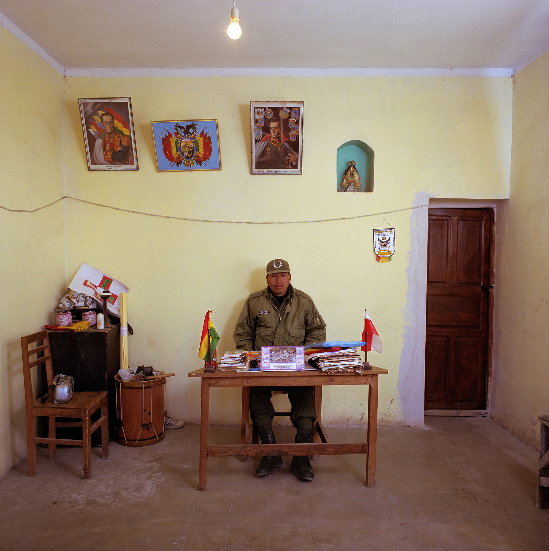 Bolivia, bureaucracy, police, (c) Jan Banning 2005.

Ivan Quispe Lopez (1978) is the only policeman in the village of Yocalla (some 8000 inhabitants). He has no means of transport, does everything on foot. And no telephone: has has to use a public phone outside his office. Monthly salary: 900 bolivianos (euro 100, $ 113).

Ivan Quispe Lopez (1978), de enige agent van politie in Yocalla, een dorp van circa 8000 inwoners, ten noorden van de stad Potosi. Hij werd in februari 2005 in Yocalla benoemd. Hij heeft geen vervoermiddel, doet zijn werk dus te voet. Het bureau beschikt ook niet over een telefoon, daarvoor gebruikt de agent de openbare telefoon aan de buitenmuur van de politiepost. Thuis heeft Quispe Lopez een schrijfmachine, op het bureau niet. "De mensen zijn slecht hier", vindt Quispe Lopez, "ze werken niet mee, ze verwarren de zaak." Hij zou liever als detective of verkeersagent in de stad Potosi werken. Maandsalaris: 900 Bolivianos (100 euro).