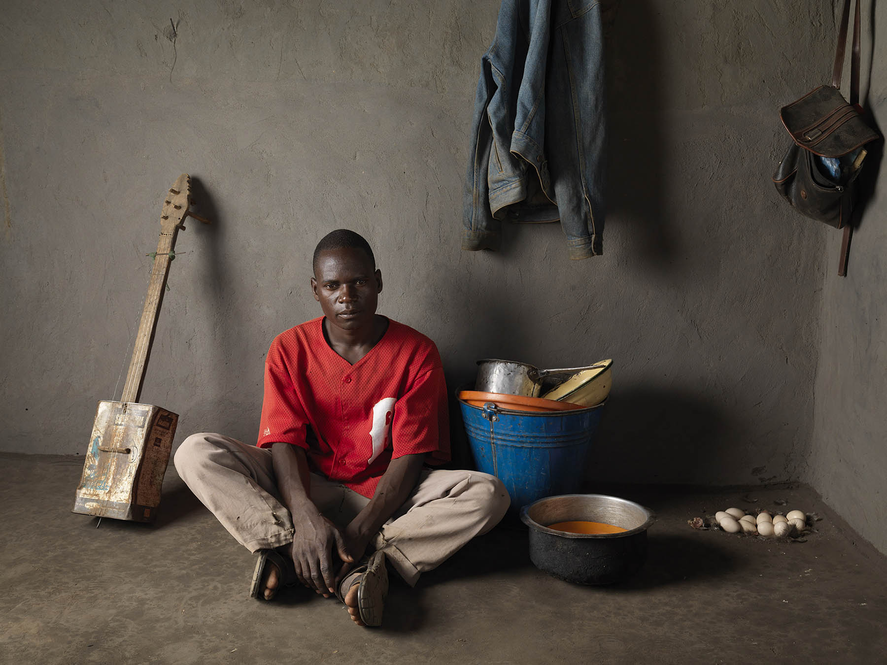 Malawi, Dickson village.  “Banjo Man” (previously “Banjo Boy”) Mahamudi Charles (25) in the house of his parents.