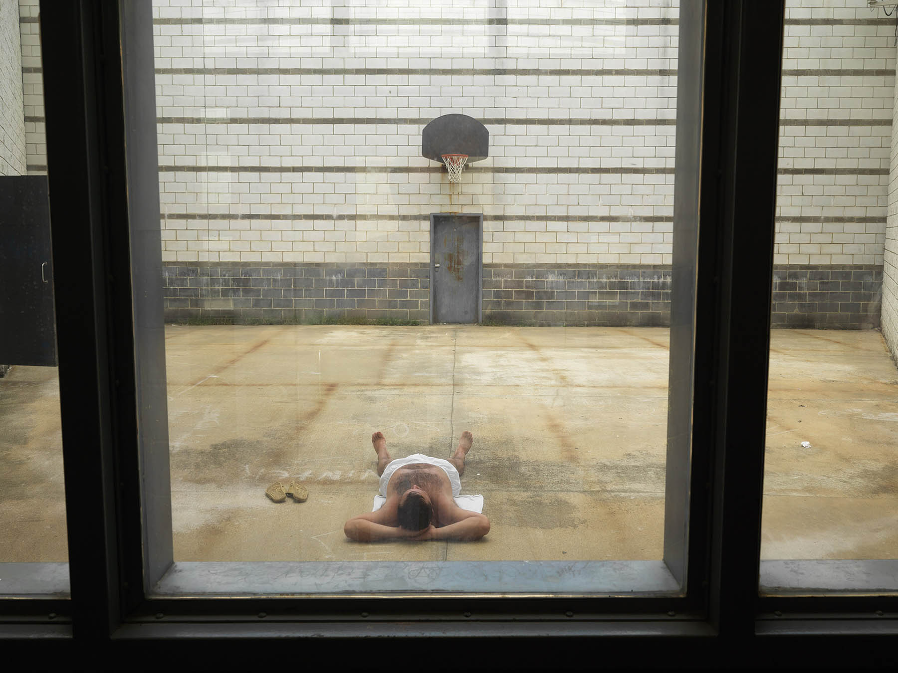 USA, GA, June 2012. Sunbathing detainee in courtyard in Putnam County Jail in Eatonton.USA, Georgia, juni 2012. Zonnenede arrestant op de luchtplaats van het cellenblok van de sheriff's politiebureau van Putnam County in Eatonton.